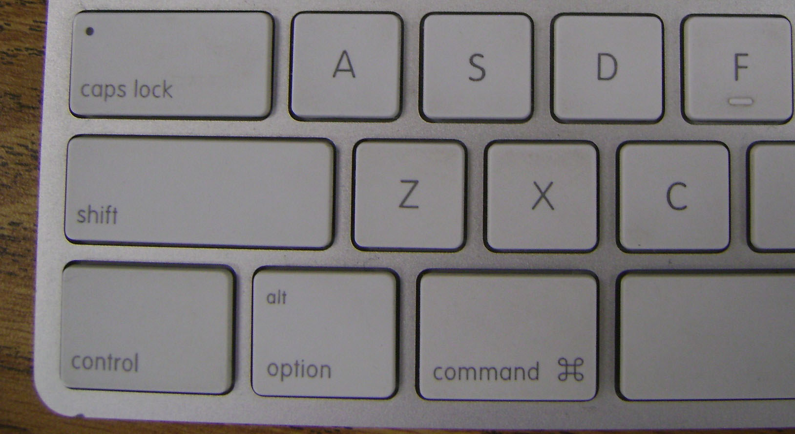 A view of the lower left corder of a white keyboard with black lettering. The first three keys on the bottom row are 'control', 'alt / option', and 'command'.